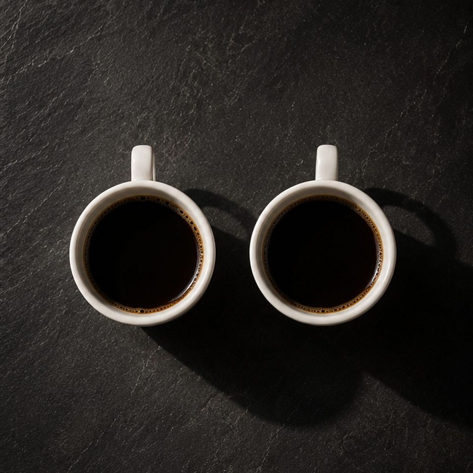 Zwei identische Tassen schwarzer Kaffee nebeneinander von oben